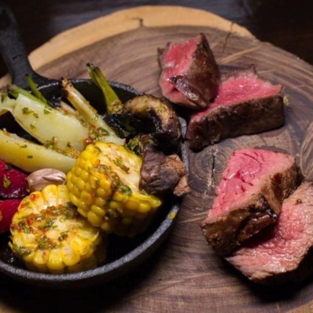 Grilled steak and vegetables served on a wooden board